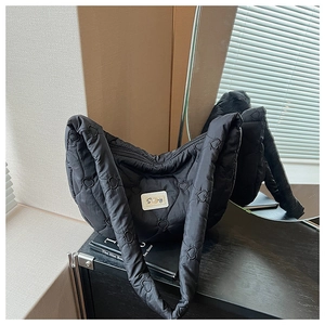Détail du sac hobo matelassé noir avec motifs de cœur sur un comptoir en bois