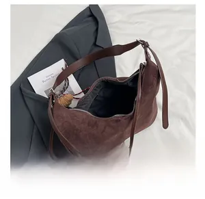 Detail view of large brown faux suede hobo bag with zipper and plush ball charm