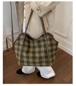 Detail of green and brown checkered tweed tote bag with leather straps on a model