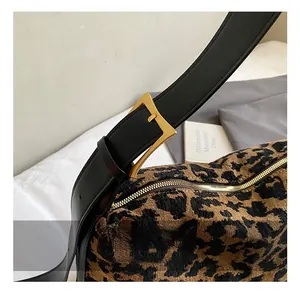 Detail of leopard print faux suede bag with black leather strap and golden metal buckle