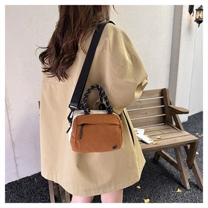 Detailed view of the corduroy texture and adjustable strap on the brown crossbody bag
