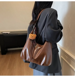Detail view of large brown vintage tote bag with plush bear charm and striped scarf
