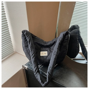 Détail du sac à bandoulière noir matelassé en forme de cœur avec patch de marque