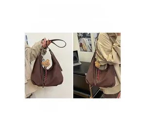Detail view of brown faux suede hobo bag with a cute bear charm and silver hardware