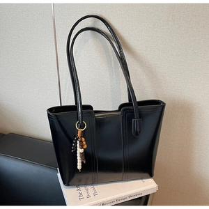 Dettaglio di una grande borsa tote nera con ciondolo a nappa su libri d'arte strutturati