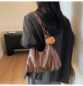 Detail of dark brown hobo bag with teddy charm and scarf on a model for daily commute