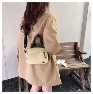 Detail of color-block casual handbag featuring avocado green trim and woven rope handle