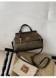 Detail of olive green suede crossbody bag with gold key charm and rotating lock
