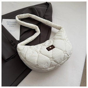 Détail du sac matelassé blanc en forme de cœur avec logo sur une veste grise