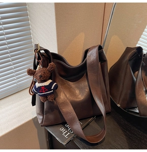 Détail du sac seau mat marron foncé avec charmant ours en peluche sur bois noir