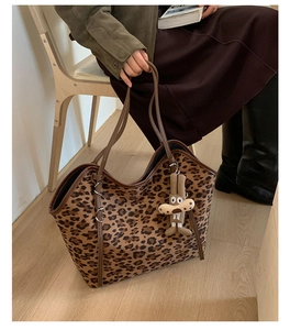 Detail of leopard print tote bag with brown leather handles and a cute knit charm