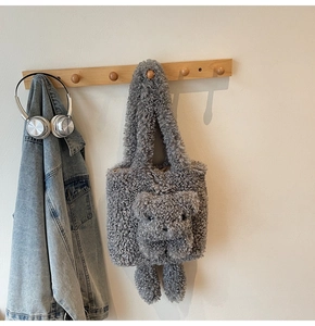 Détail du sac à main gris en peluche avec motif d'ours 3D suspendu à un crochet