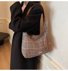 Detail of tweed hobo bag with red houndstooth pattern and brown leather strap