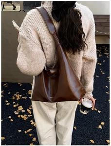 Detail of dark brown leather tote bag with contrast stitching in autumn street setting