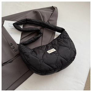 Détail du sac bandoulière matelassé noir avec motifs cœurs et écusson logo carré