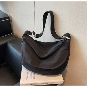 Close-up of black nylon crescent crossbody bag featuring an adjustable strap and white buckle