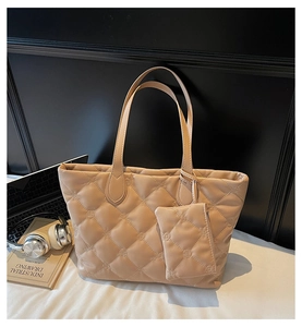 Detailed view of beige quilted tote bag set with floral stitching and a small charm pouch