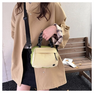 Detail of yellow and green canvas crossbody bag with thick rope handles on a model