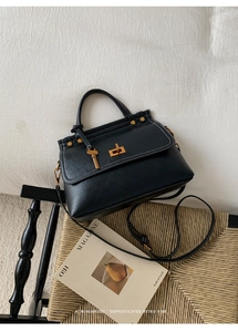 Detailed view of retro black leather handbag with white stitching and gold hardware