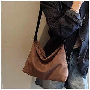 Detail of soft dark brown suede hobo bag with black shoulder strap worn by model