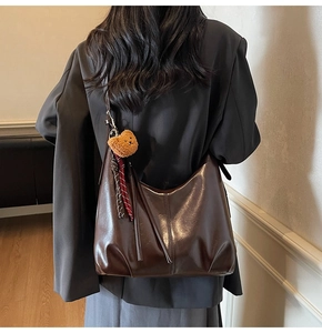Detail of dark brown leather hobo bag showing adjustable strap and cute bear charm
