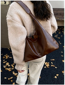 Detail of dark brown leather tote bag with white stitching and brand lettering logo