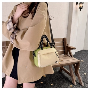 Detail of color-block nylon crossbody bag showing avocado green side and climbing rope handle