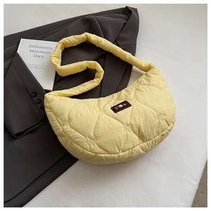 Détail du sac dumpling jaune matelassé en cœur avec étiquette perle sur blazer