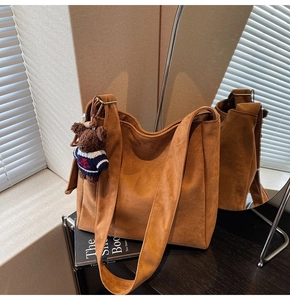Détail du sac seau en daim marron mat avec pendentif ours en peluche et lumière chaude
