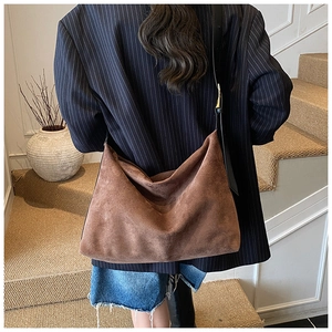 Sac fourre-tout en daim marron porté à l'épaule pour voir la taille et le drapé