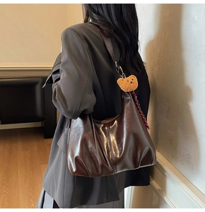 Detail of dark brown tote bag with plush bear charm and plaid scarf accent