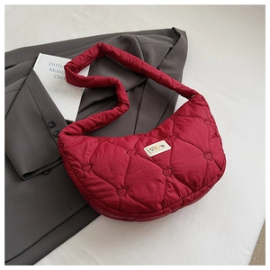 Détail d'un sac à bandoulière matelassé rouge avec motif cœur sur fond gris
