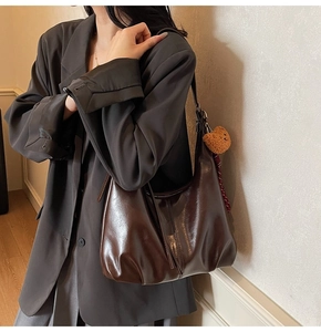 Deep brown oversized hobo bag with pleated texture and cute bear charm shown on shoulder