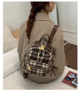 Detail of a retro plaid backpack with gold metal zippers and textured winter fabric