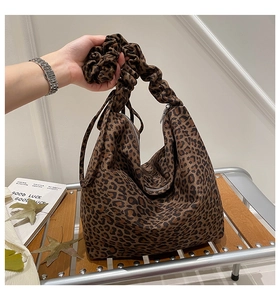 Detail of leopard print tote bag featuring a ruched scrunchie handle and smooth zipper closure