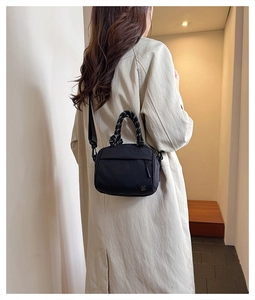 Detail view of black nylon handbag with black and white braided rope handles for women