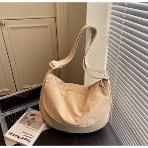 Detail of beige nylon crescent bag with wrinkled texture and adjustable shoulder strap