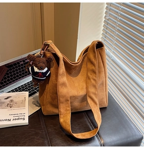 Détail du sac seau en daim marron avec un joli pendentif en forme d'ours en peluche
