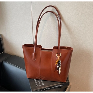 Dettaglio borsa tote in pelle marrone scuro con ciondolo in perline di legno vintage