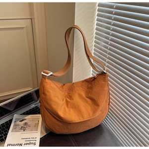 Detail of caramel orange nylon crescent bag showing water-resistant texture and strap