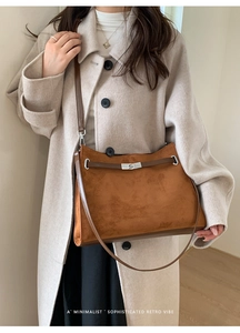 Detail of vintage brown suede tote with metal twist lock and leather strap on a model