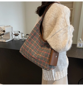 Detail of vintage houndstooth tote bag with brown leather accents in a cafe setting