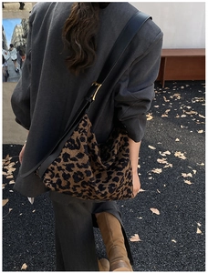 Détail d'un sac hobo à motif léopard avec tissu texturé et bandoulière en cuir noir