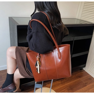 Dettaglio di una grande borsa tote marrone in pelle PU con ciondolo a nappine di perline