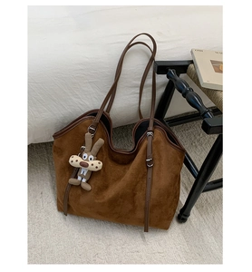 Detail of dark brown leopard tote bag with soft suede texture and a cute rabbit charm