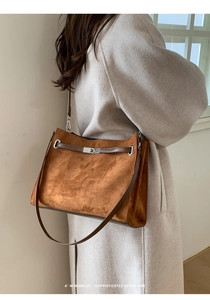 Detail of brown suede shoulder bag showing silver twist lock and retro leather strap texture
