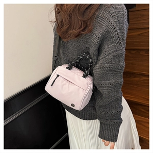 Detail view of pink nylon crossbody bag with woven rope handle and metal logo