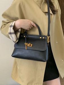 Vintage black crossbody bag with white stitching, gold lock, and key charm detail