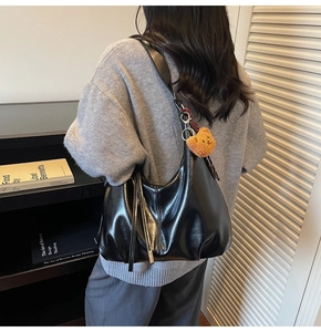 Detailed look at the black glossy PU leather shoulder bag featuring a cute brown bear charm