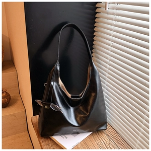 Detail of a large black leather hobo tote bag with shadow lighting on a wooden desk